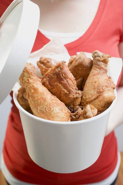 Vista de cerca de la mujer sosteniendo cubo de palillos de pollo fritos - foto de stock