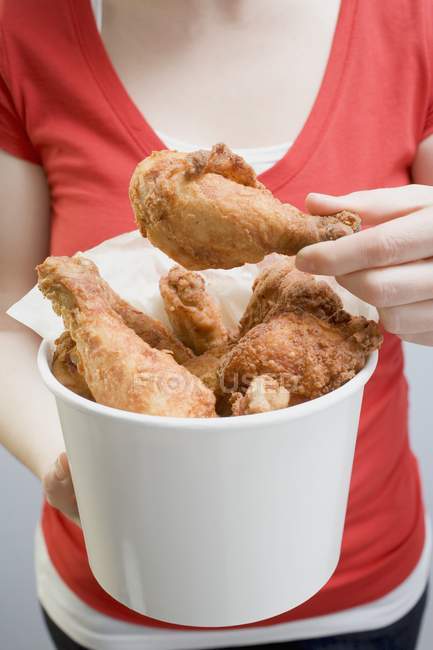Closeup view of woman holding deep-fried chicken drumsticks — Stock Photo