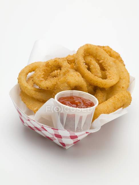 Onion rings with ketchup in paper dish — Stock Photo