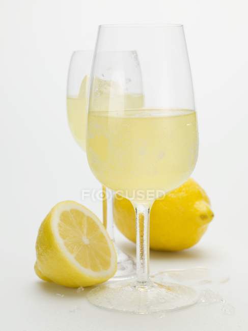 Vista de cerca de dos vasos de Limoncello y limones frescos - foto de stock