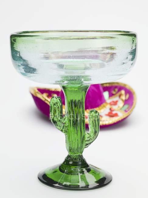 Vue rapprochée du verre à cocktail vert en forme de cactus avec chapeau mexicain sur la surface blanche — Photo de stock