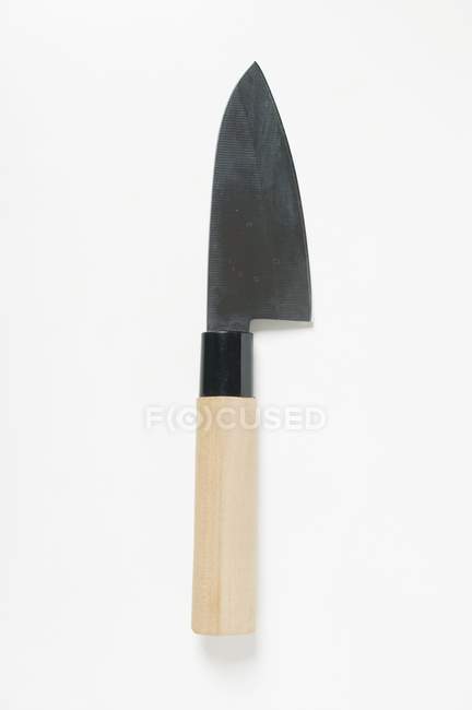 Vista de cerca de un cuchillo de cocina asiático en la superficie blanca - foto de stock