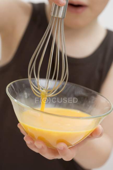 Child holding bowl of egg yolks — Stock Photo
