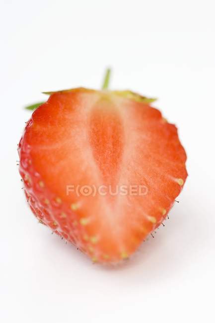 Closeup view of a strawberry half on white surface — Stock Photo