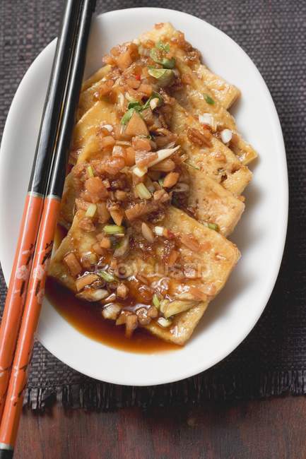 Marinierter Tofu mit Knoblauch auf weißem Teller mit Holzstäbchen — Stockfoto