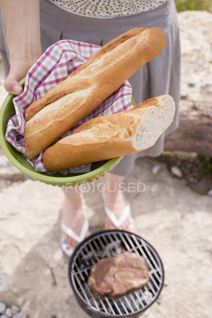 Woman holding baguettes in bowl — Stock Photo