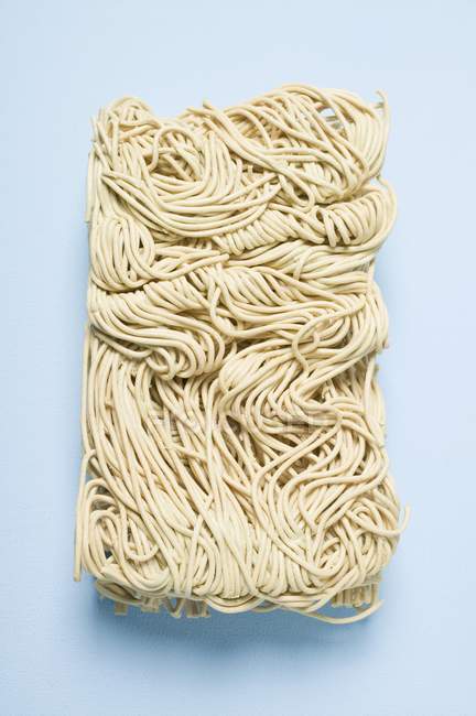 Top view of egg noodles block on a blue surface — Stock Photo