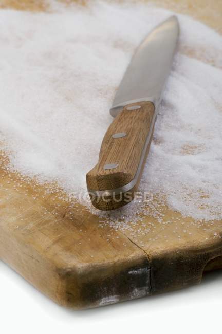 Knife and sugar on chopping board — Stock Photo