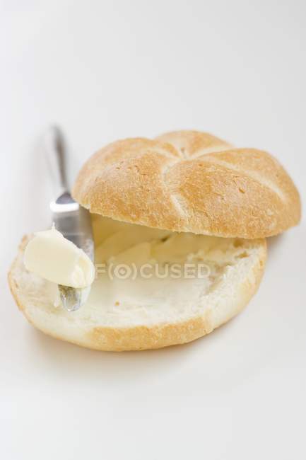 Buttered bread roll with knife — Stock Photo