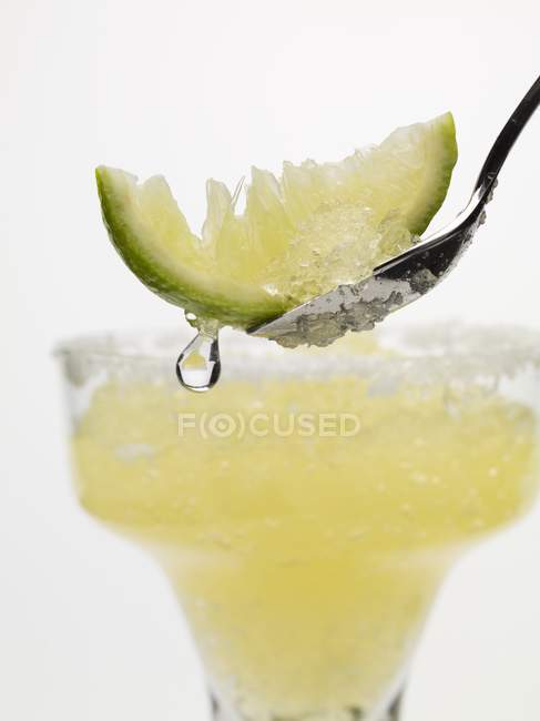 Margarita congelada con cuña de lima en cuchara - foto de stock