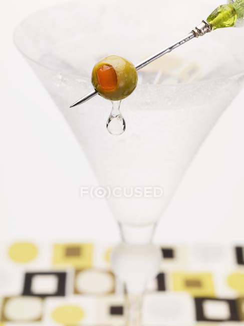 Martini with olive on cocktail stick — Stock Photo