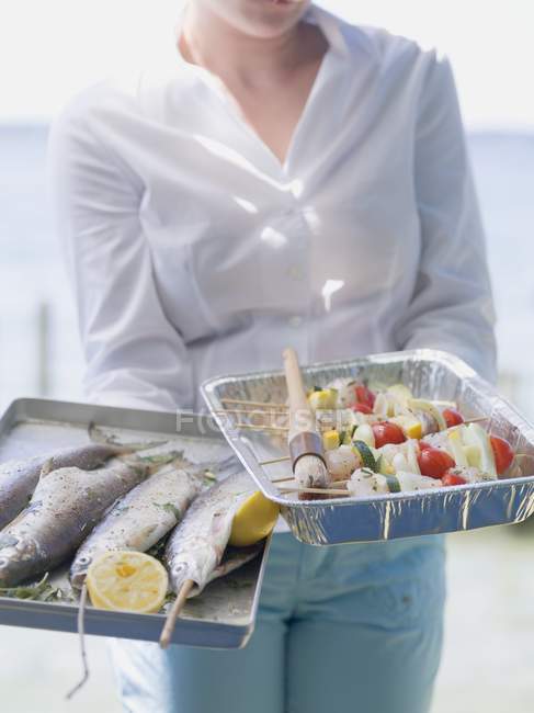 Woman holding trays of fish and kebabs — Stock Photo