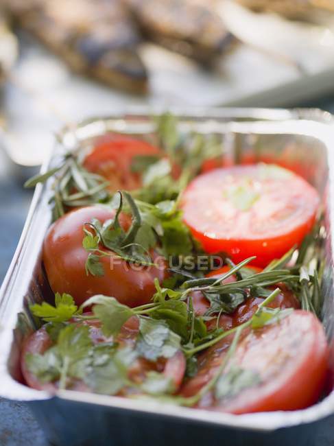 Tomatoes with fresh herbs in aluminium dish, ready for grilling — Stock Photo