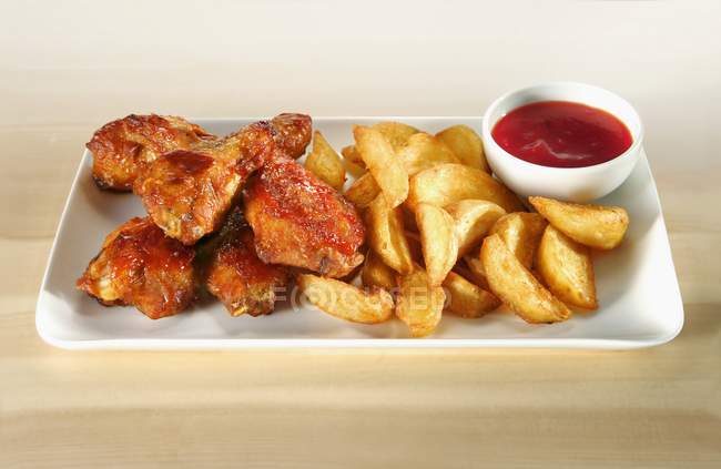 Chicken wings with potato wedges — Stock Photo