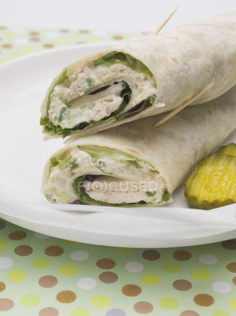 Wraps and gherkin slices on white plate over towel — Stock Photo