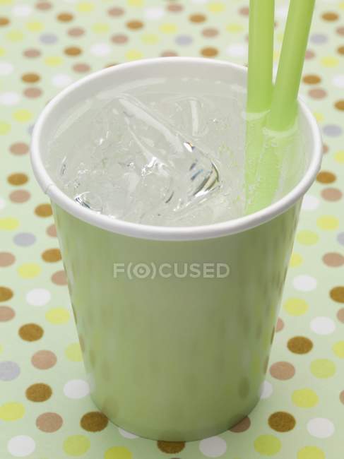Closeup view of iced water in paper cup with straws — Stock Photo