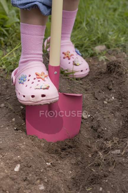 Cropped view of little girl digging with a spade — Stock Photo