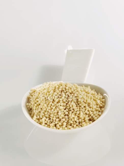 Spoonful of millet on white surface — Stock Photo