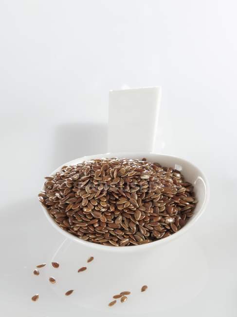 Spoonful of linseed on white surface — Stock Photo