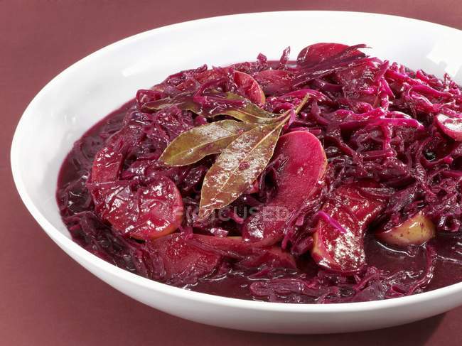 Apple red cabbage on white plate over red surface — Stock Photo
