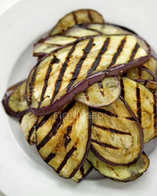 Grilled aubergine slices on white plate — Stock Photo