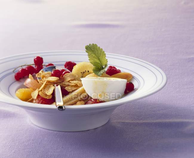 Ensalada de frutas con yogur y copos de maíz - foto de stock