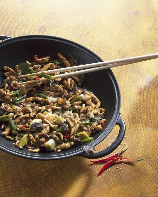 Frango com cogumelos shiitake e cebolinha em wok com paus de madeira — Fotografia de Stock