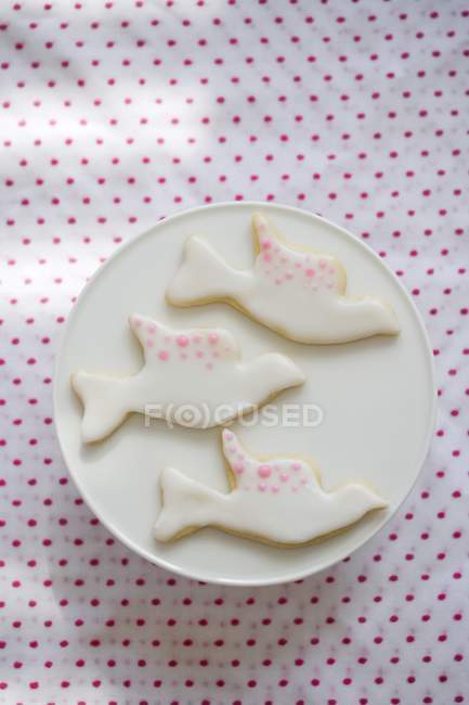 Вид сверху на три печенья в форме голубя с белой и розовой глазурью — стоковое фото