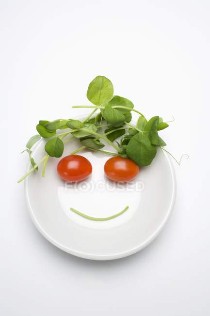 Овочеве обличчя в супній тарілці над білою поверхнею — стокове фото