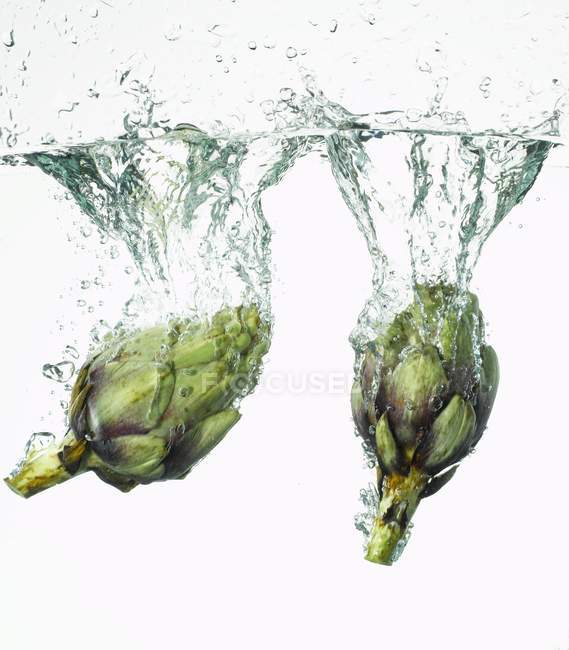 Alcachofas que caen al agua - foto de stock