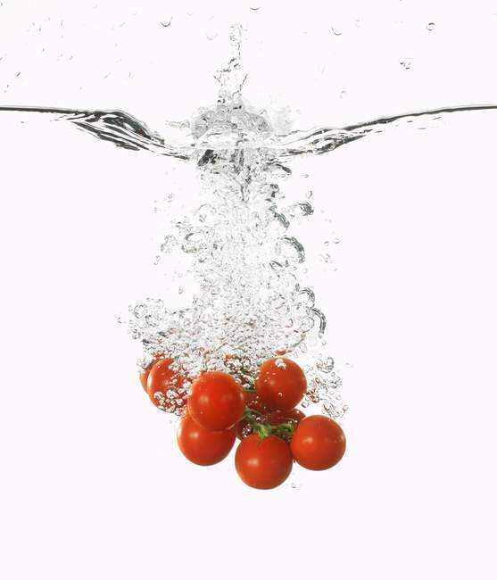 Tomates cerises tombant dans l'eau — Photo de stock