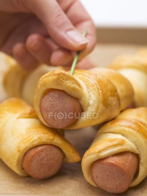 Hand pushing cocktail stick into roll — Stock Photo
