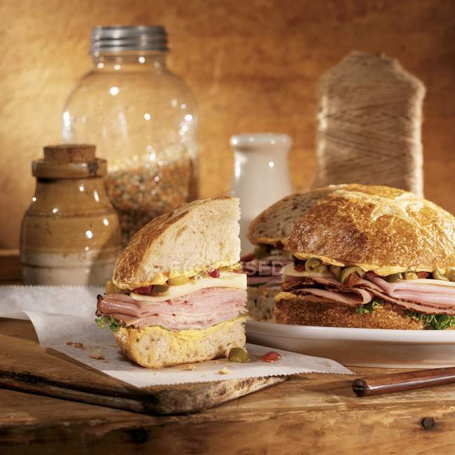 Muffuletta sliced on wooden desk and plate over wooden background — Stock Photo