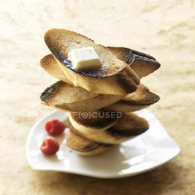 Vista de primer plano de tostadas apiladas con manteca y frambuesas - foto de stock