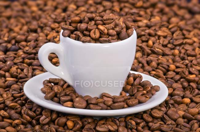 Granos de café en taza de café expreso - foto de stock