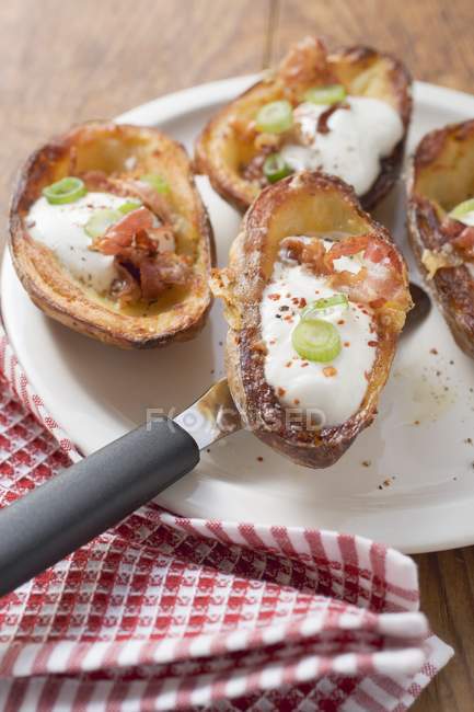 Baked potato skins with bacon and sour cream  on white plate over towel — Stock Photo