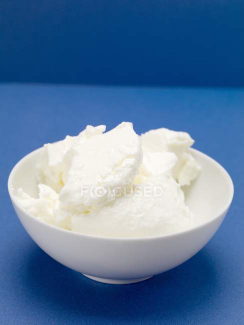 Closeup view of Quark in small white bowl on blue surface — Stock Photo