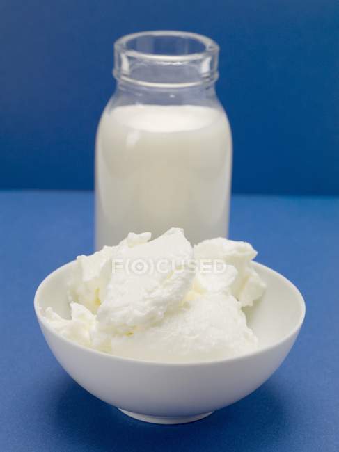 Quark in bowl in front of bottle of milk — Stock Photo