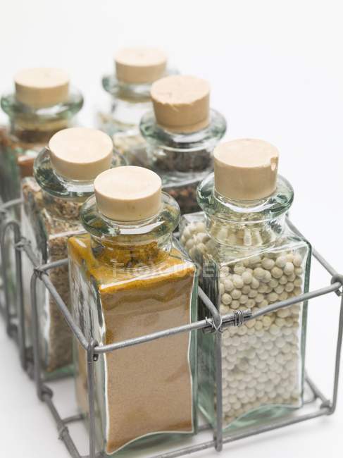Vista de cerca de varias especias en pequeñas botellas de vidrio - foto de stock