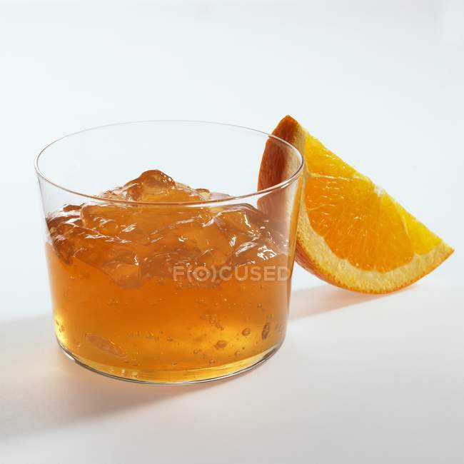 Orange jelly in glass and orange wedge — Stock Photo