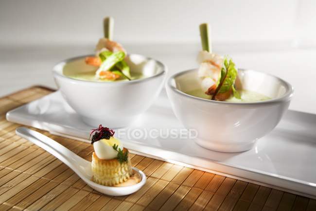 Closeup view of cress soup with prawns on lemon grass skewers — Stock Photo