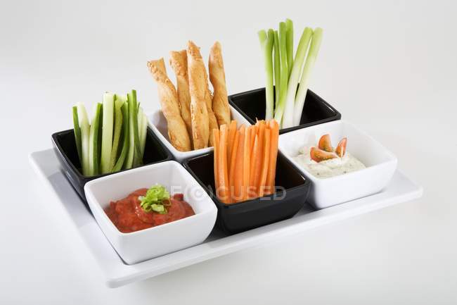 Tablett mit Gemüsesticks, pikanten Strohhalmen und Dips auf weißem Hintergrund — Stockfoto