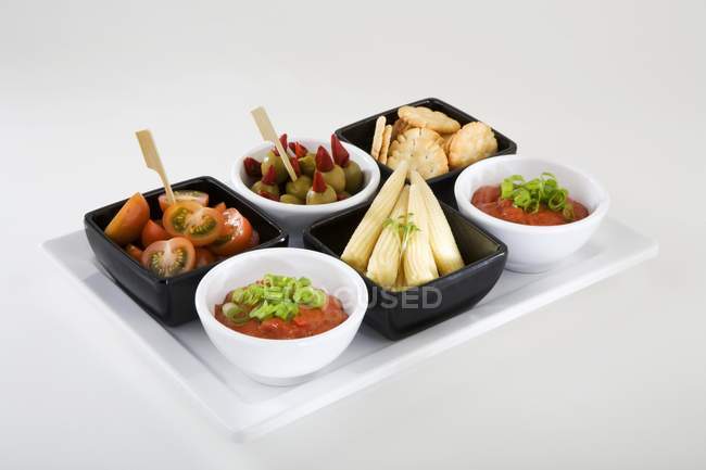 Tray of antipasti with black and white bowls — Stock Photo
