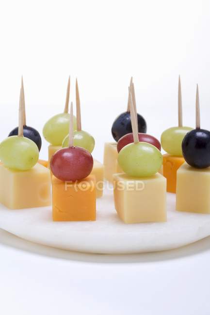 Käse und Trauben auf Stöcken — Stockfoto