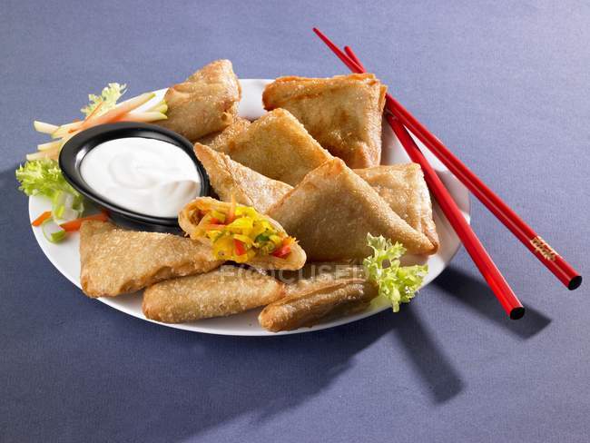 Elevated view of Samosas with dip, vegetables and chopsticks on plate — Stock Photo