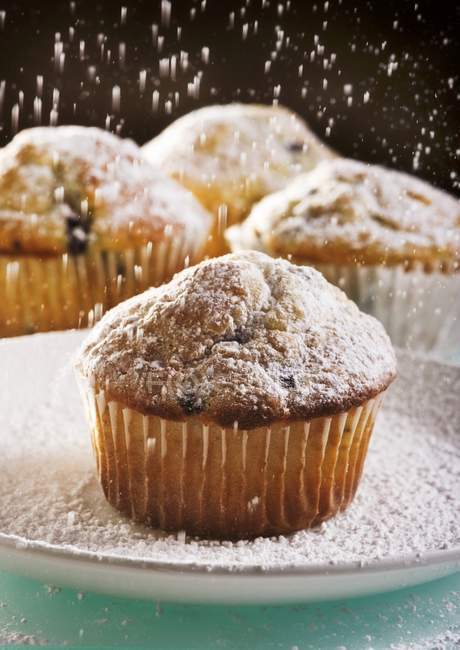 Muffins de arándanos siendo polvoreados - foto de stock