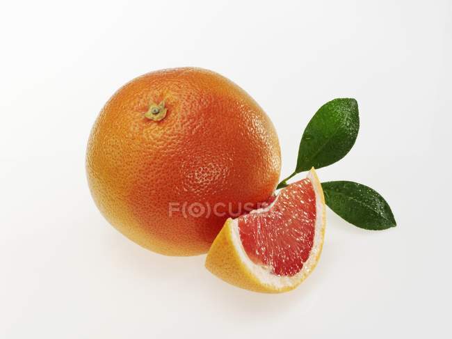 Рожевий грейпфрут зі скибочками та листям — стокове фото