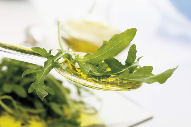 Rocket on spoon with olive oil — Stock Photo