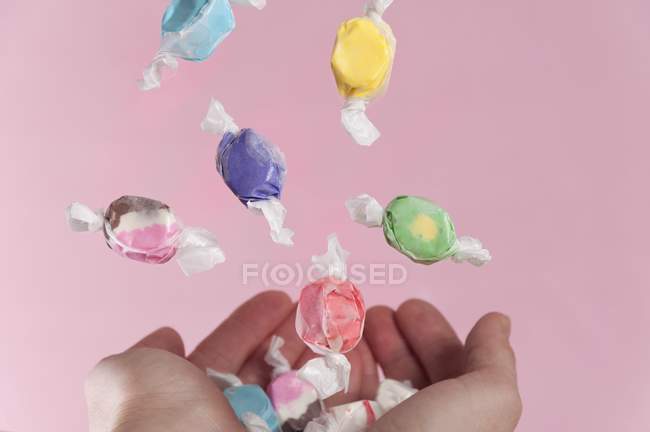 Vista recortada de las manos la captura de dulces que caen - foto de stock