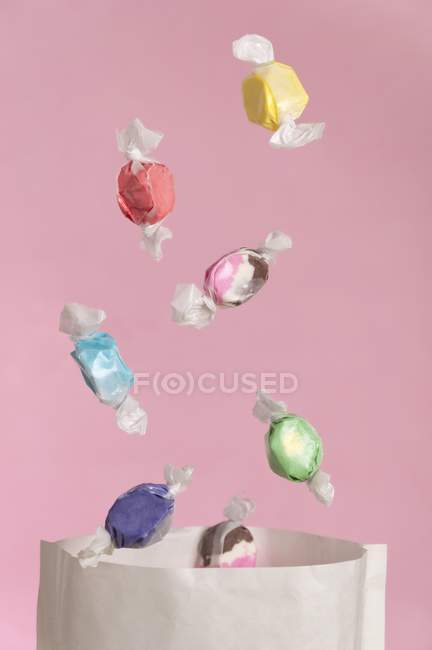 Vista de primer plano de dulces que caen a la bolsa de papel - foto de stock
